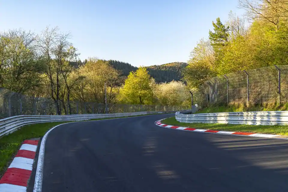 Freie Kurve am Nürburgring zwischen Leitplanken und Bäumen.