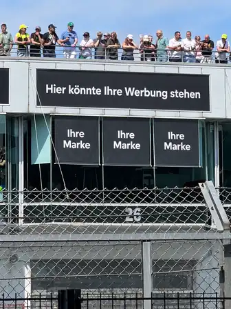 Gestaltungsvorschlag für eine Lounge-Außenansicht mit großem Werbebanner und drei gebrandeten Sonnenschutzflächen.