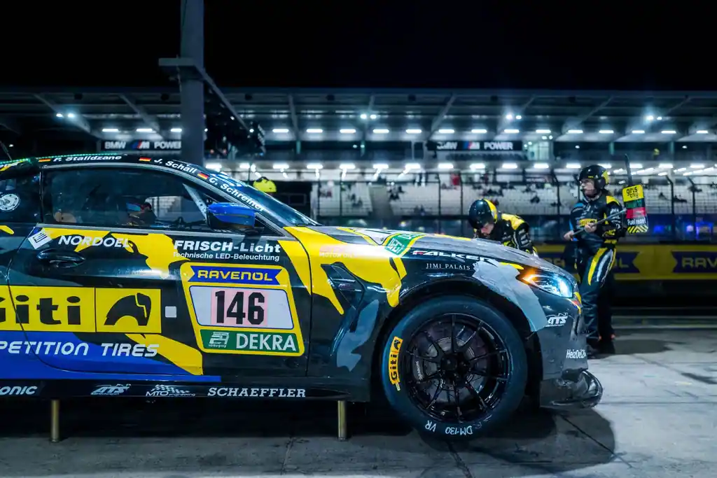 Front eines BMW-Rennwagens in der Nürburgring-Boxengasse bei Nacht.